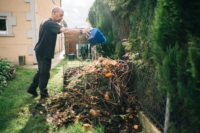 Man leegt afval bij composthoop