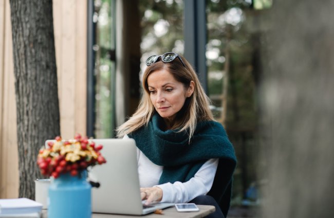 Vrouw in de tuin met laptop in de herfst