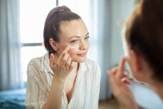 Vrouw doet creme op voor de spiegel