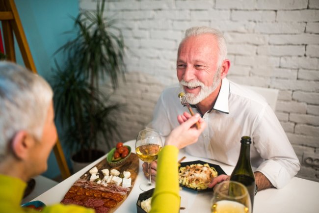 Vrouw voert man lekker eten aan tafel