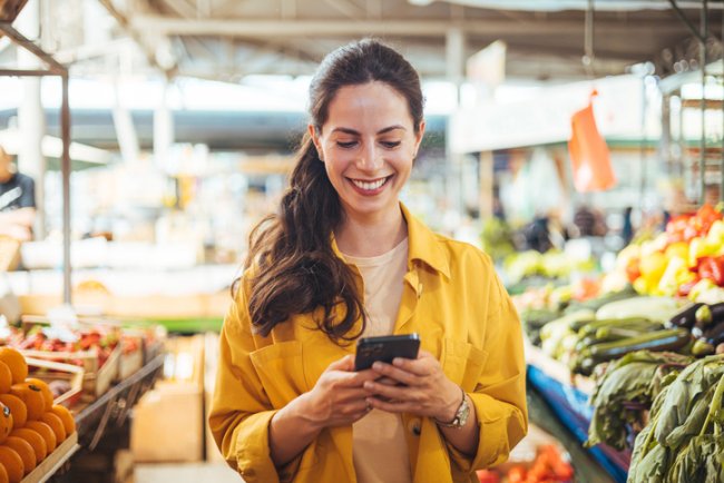 Vrouw op de markt met mobiele telefoon