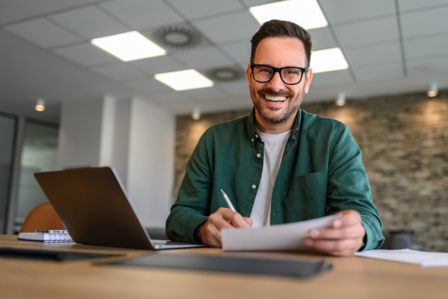 Financieel adviseur lacht, laptop en papierwerk