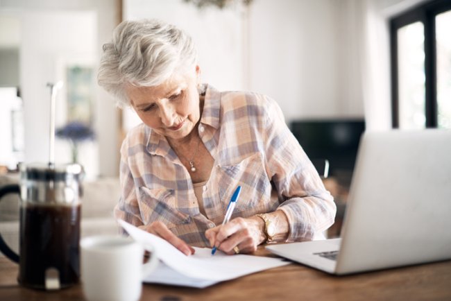 Oudere dame thuis bezig met administratie