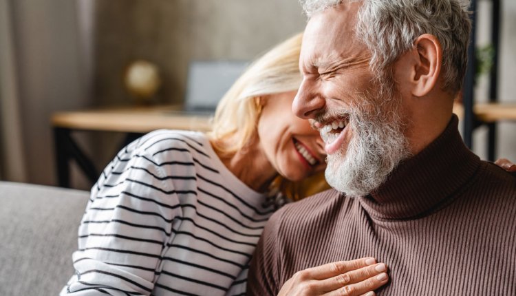 Gelukkig stel thuis lachend op de bank