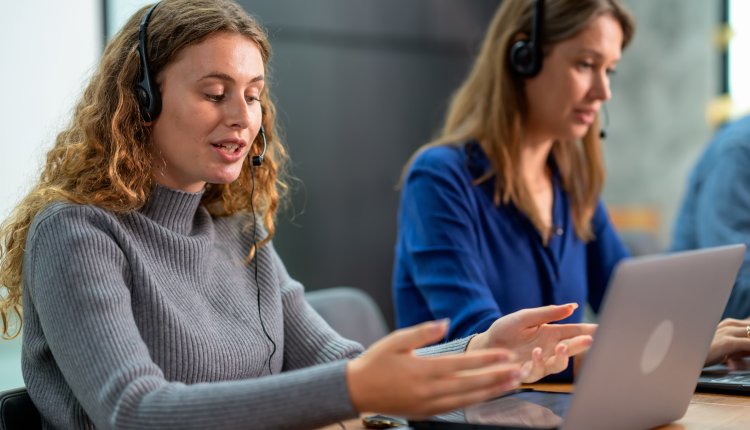 Bank helpdesk vrouw legt uit aan klant met laptop, vrouwelijke collega naast haar