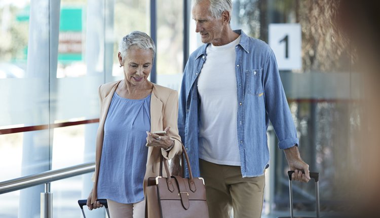 Ouder paar op vliegveld met rolkoffer