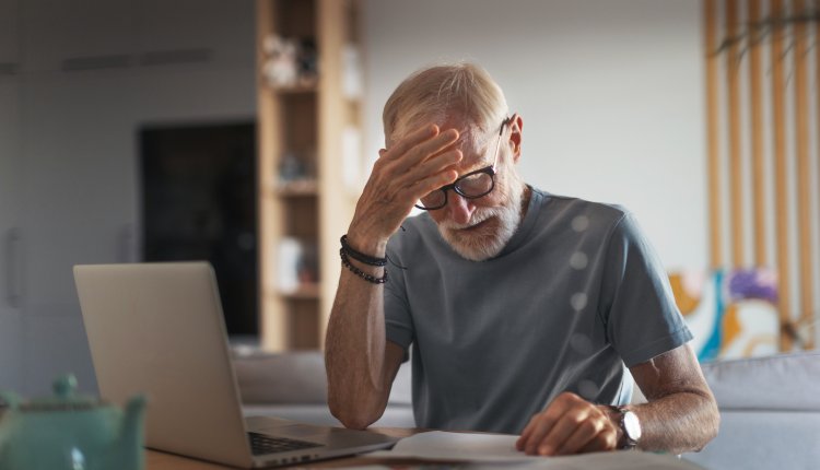 Oudere man aan het werk achter zijn laptop