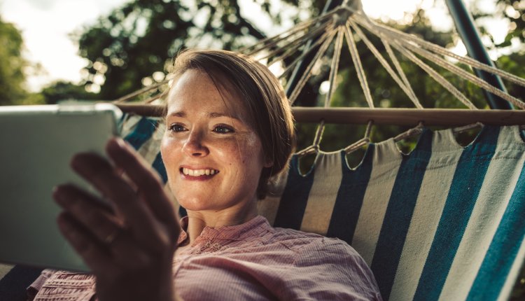 Knappe vrouw in hangmat geniet met tablet