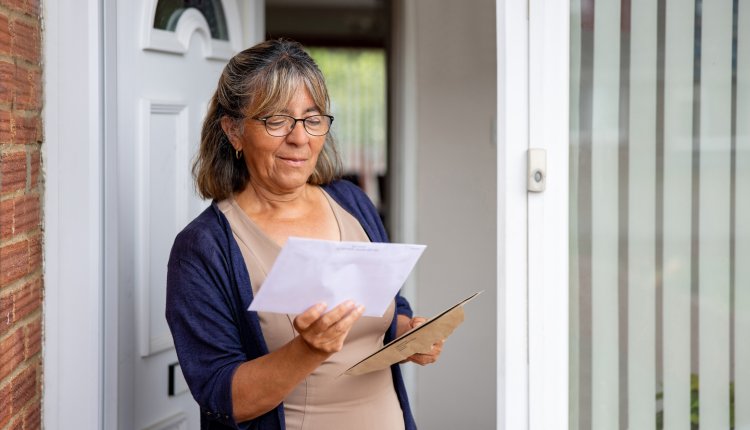 Vrouw opent brief bij de voordeur