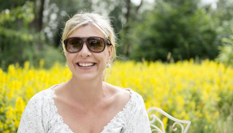 Vrouw met hooikoorts in veld vol bloemen