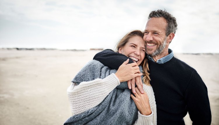 Vrolijk koppel op het strand met wat kouder weer