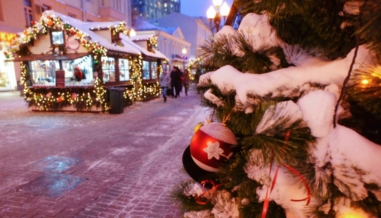 Een sfeervolle kerstmarkt met verlichte kraampjes, sneeuwbedekte takken en kerstdecoraties op de voorgrond