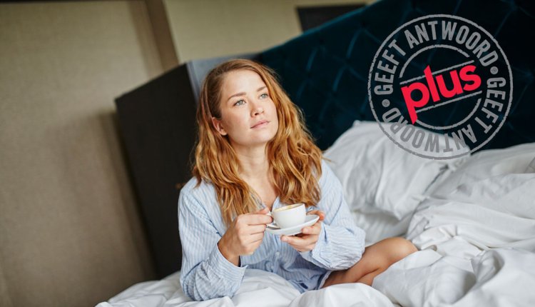 Vrouw wordt wakker met kop koffie op bed