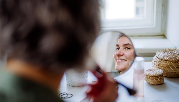 Vrouw maakt haar gezicht op in de spiegel