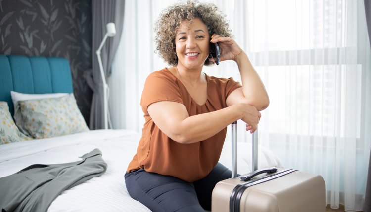 Vrouw op bezoek in een hotelkamer met rolkoffer