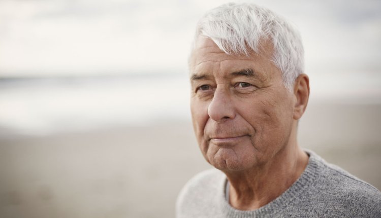 Oudere man op het strand met trui aan