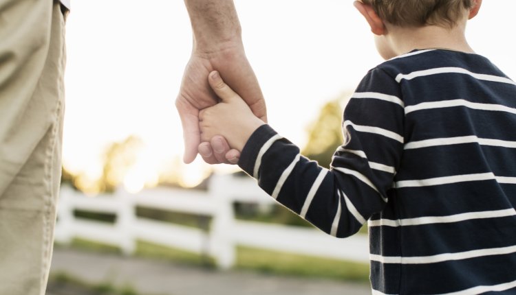 Vader houdt hand van zoon vast