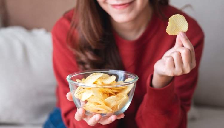 Vrouw eet chips uit kommetje