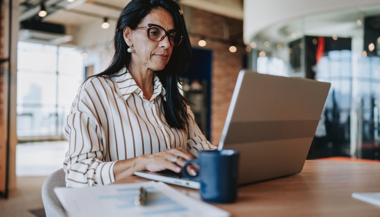 Oudere dame is bezig op haar laptop op kantoor