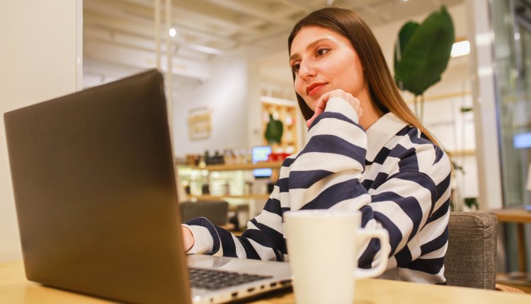 Blanke vrouw met bruin haar achter haar laptop