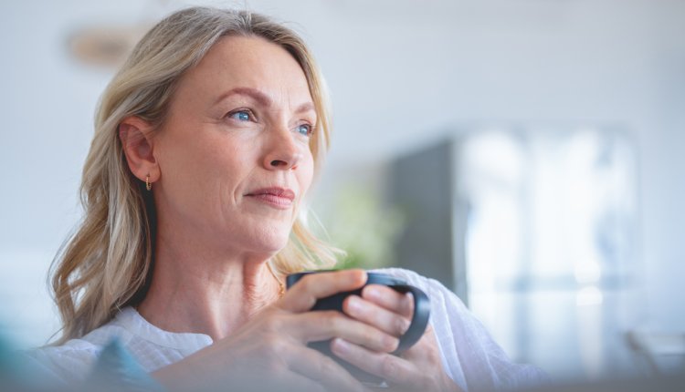 Vrouw zorgelijk met een kop koffie op de bank