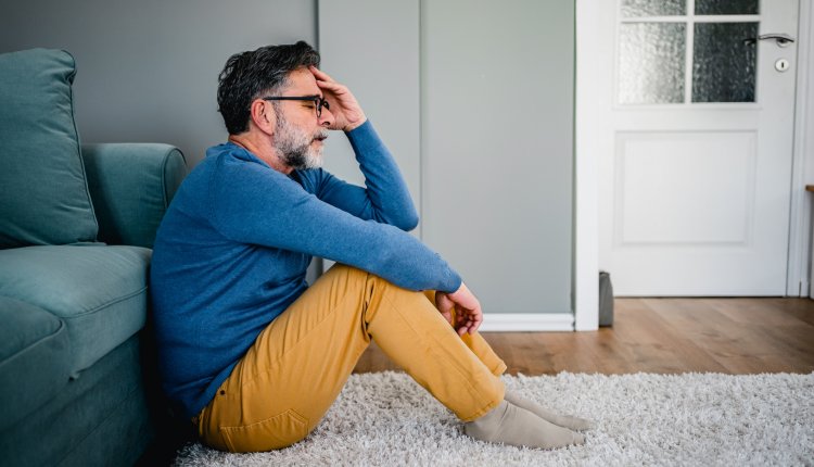 Man zit vertwijfeld op de grond in huis