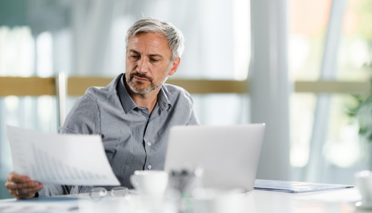 Man doet werk met papier achter laptop