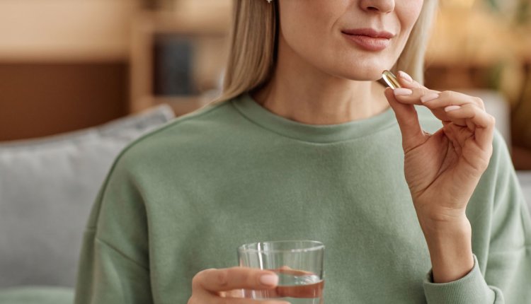 Vrouw neemt vitaminepil in met een glas water