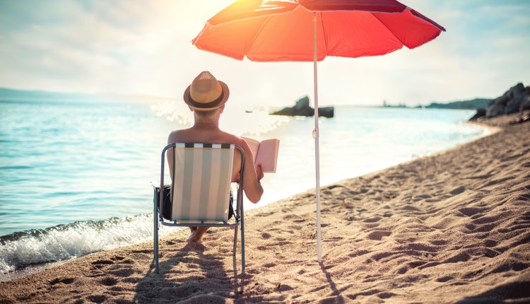 Man zit onder zijn parasol te lezen