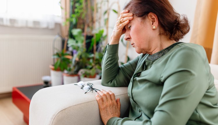 Vrouw heeft last van duizeligheid, zit op de bank