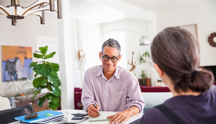 Man is thuis bezig met financien, vrouw zit tegenover hem