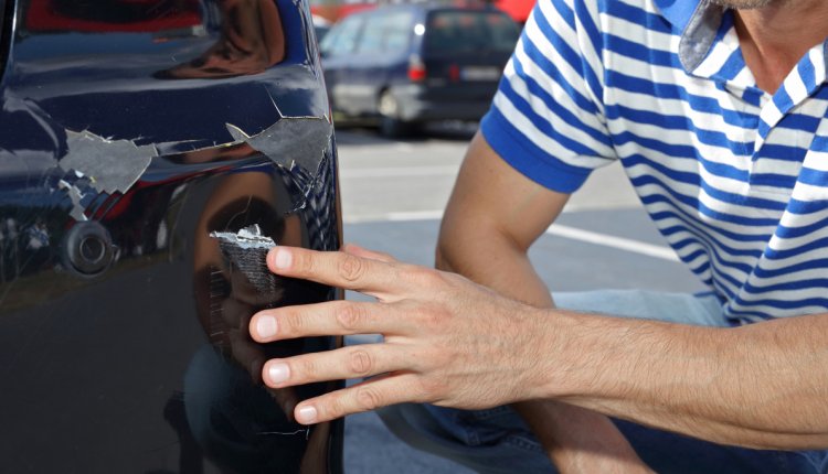 Man wijst kras op zijn auto aan