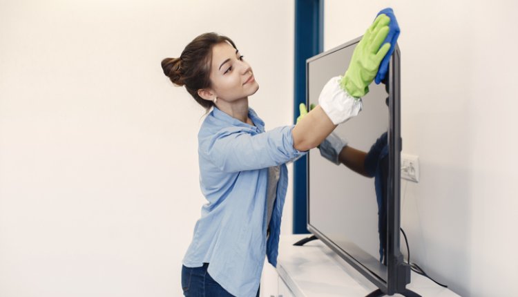 Vrouw maakt met een doek de televisie schoon