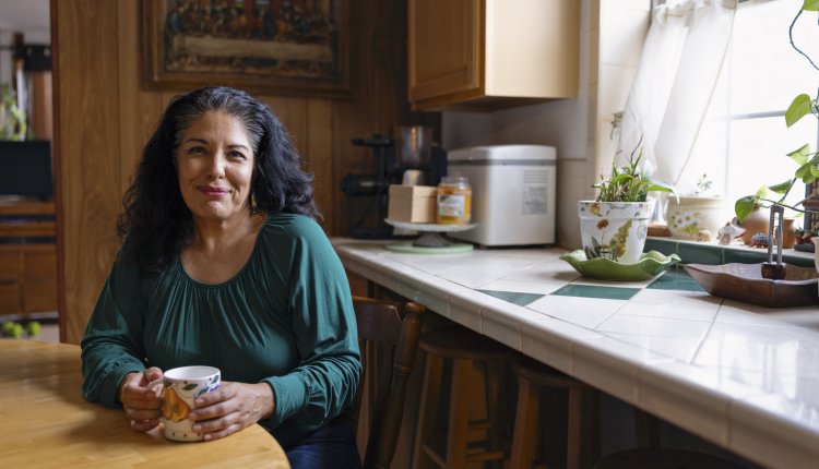 Vrouw met donker haar zit aan de keukentafel