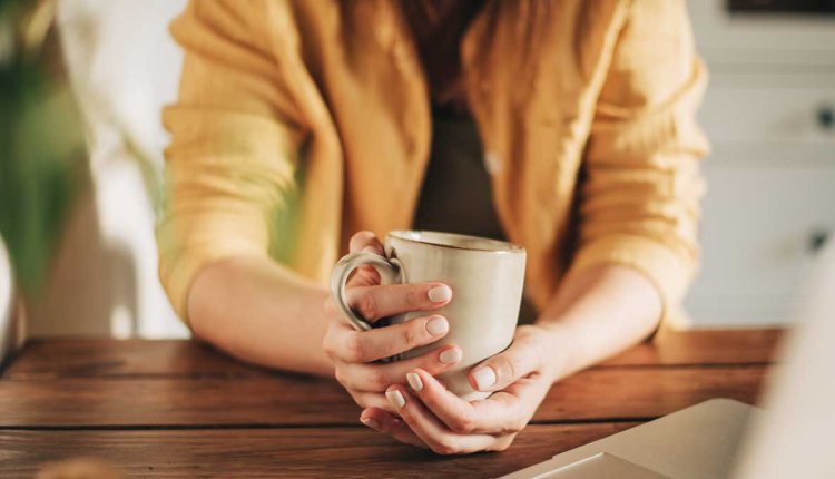 Vrouw drinkt koffie achter  laptop