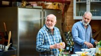 Oudere mannen zijn vrienden van elkaar samen koken in de keuken