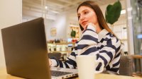 Blanke vrouw met bruin haar achter haar laptop