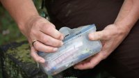 Geocache gevonden in plastic gewikkeld, man heeft in zijn handen