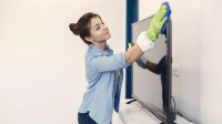 Vrouw maakt met een doek de televisie schoon