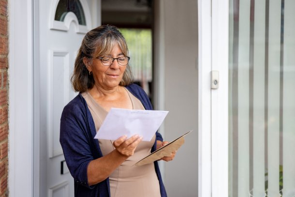 Vrouw opent brief bij de voordeur