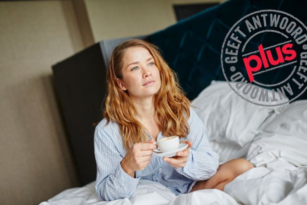 Vrouw wordt wakker met kop koffie op bed