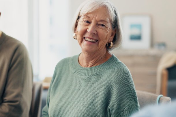 Oudere dame zit aan tafel met leeftijdsgenoten