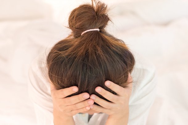 Vrouw grijpt met handen naar hoofd omdat ze stekende hoofdpijn heeft