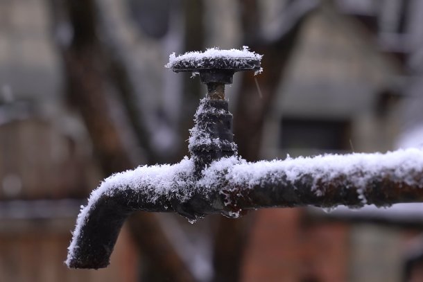 Bevroren buitenkraan in de winter, met ijs op de kraan