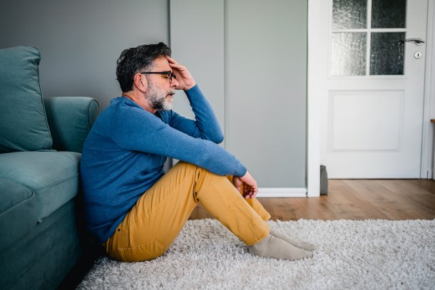 Man zit vertwijfeld op de grond in huis