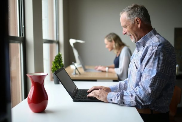 Een oudere man op zijn laptop aan het werk