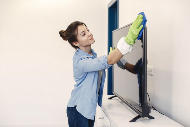 Vrouw maakt met een doek de televisie schoon